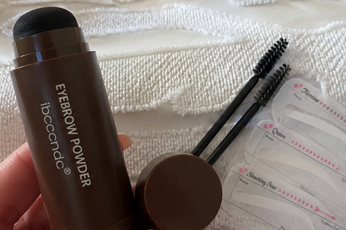 A collage showing a brown eyebrow pomade stick and its applicators, alongside swatches of the product applied to skin and several views of the product with eyebrow pencil and false eyebrow patches.